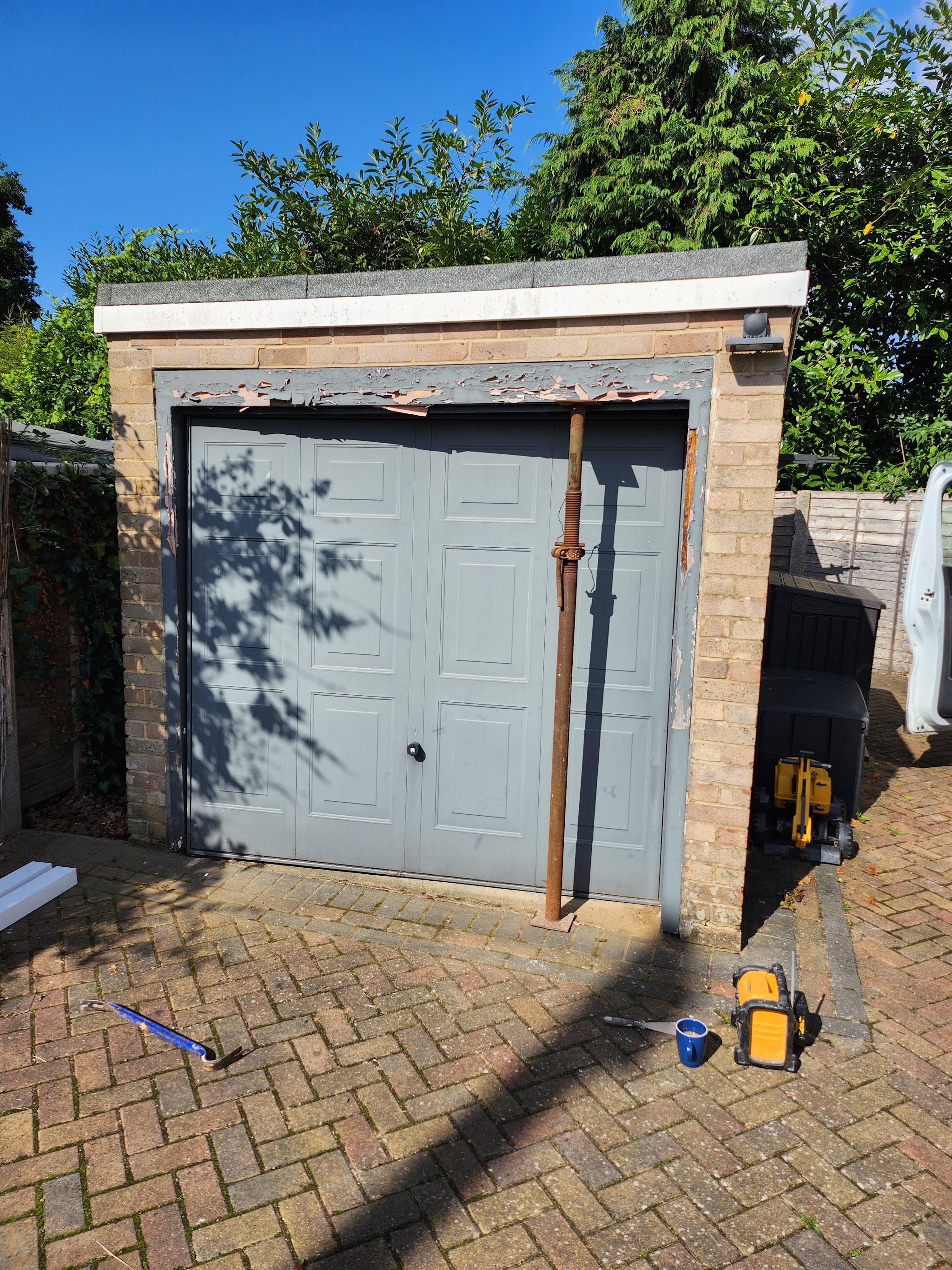 A brick garage with a grey panelled door while its frame is being worked on